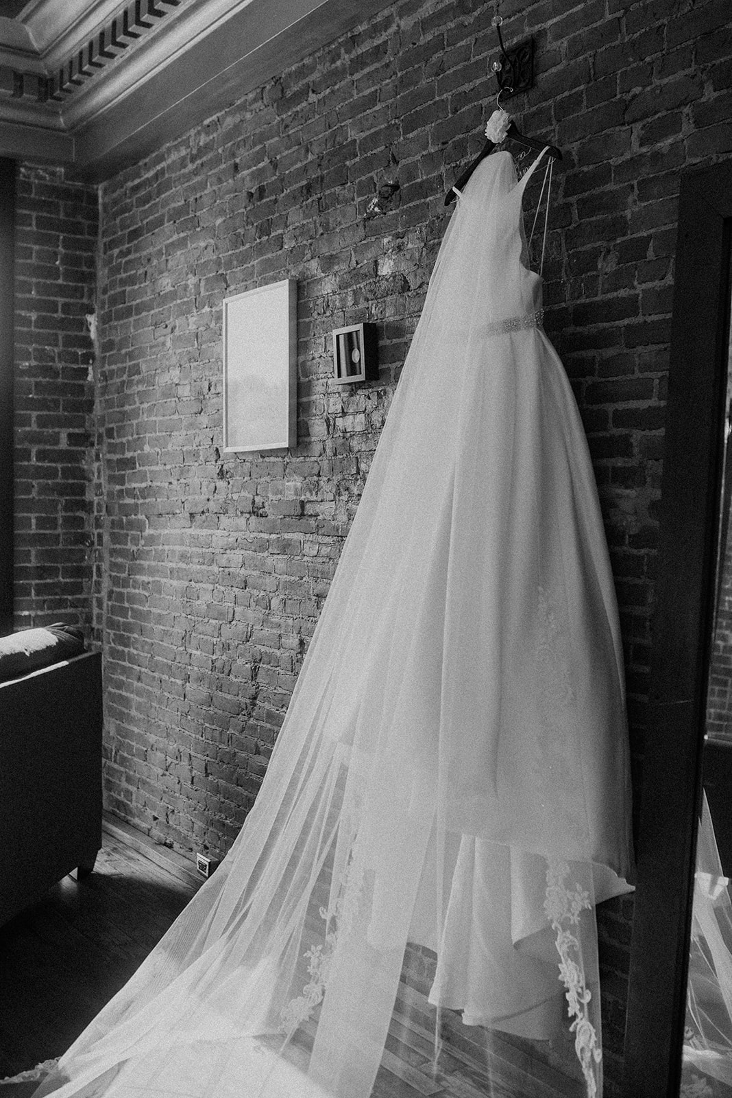 Wedding dress hanging on brick wall